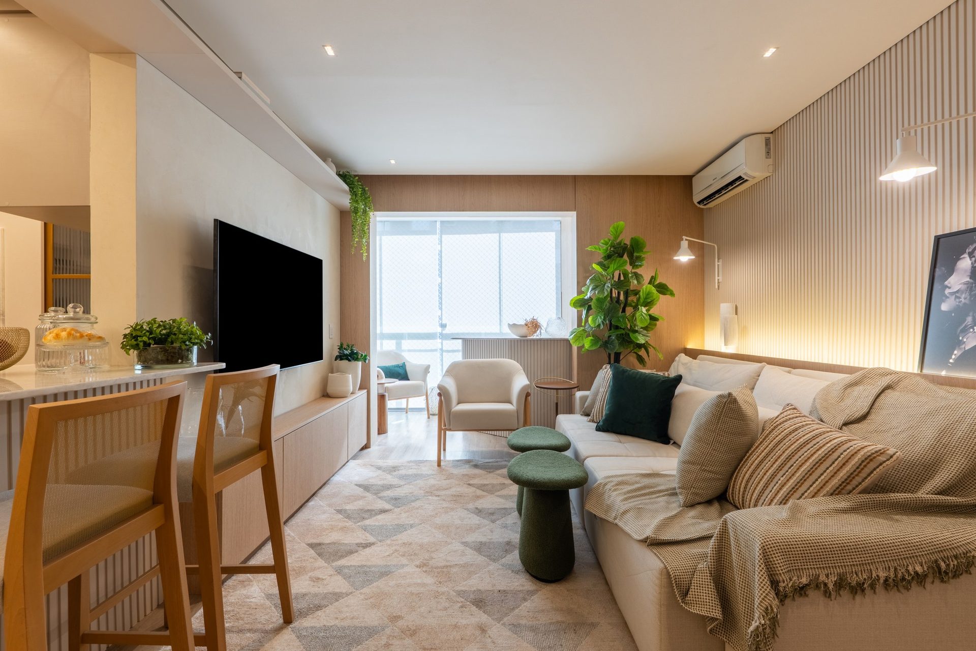 Living de apartamento com sofá claro, mesa lateral verde e bancada de refeições em madeira
